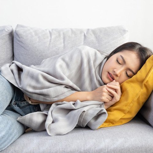 Lady rests uncomfortably on couch