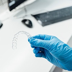 Dentist with blue glove holding clear aligner