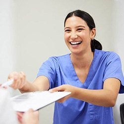 a front desk member giving a patient dental insurance forms