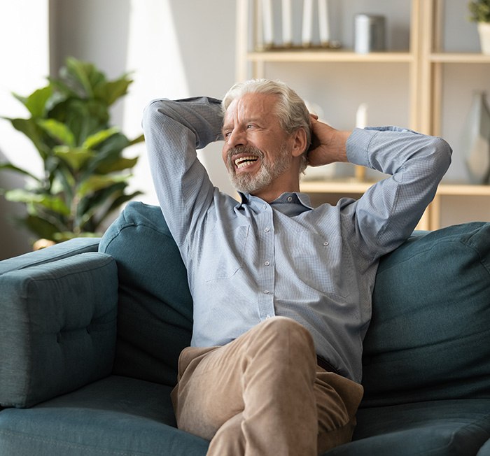 Man sitting on couch with implant dentures in Minot, ND