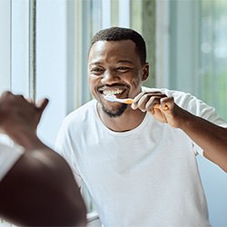 Man smiling while brushing his teeth