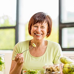 Woman smiling while eating healthy meal at home