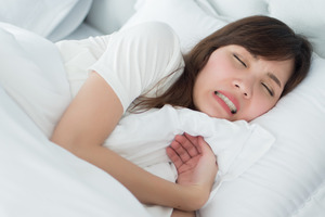 Woman sleeping in bed grinding her teeth